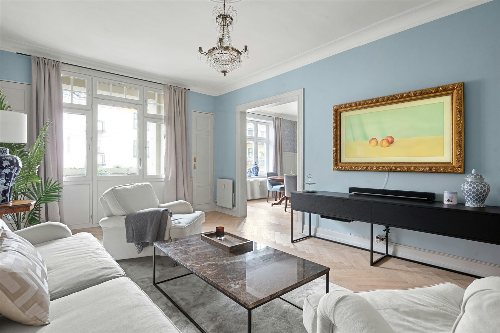 Salon haussmannien bleu clair avec moulures, lustre et grandes fenêtres